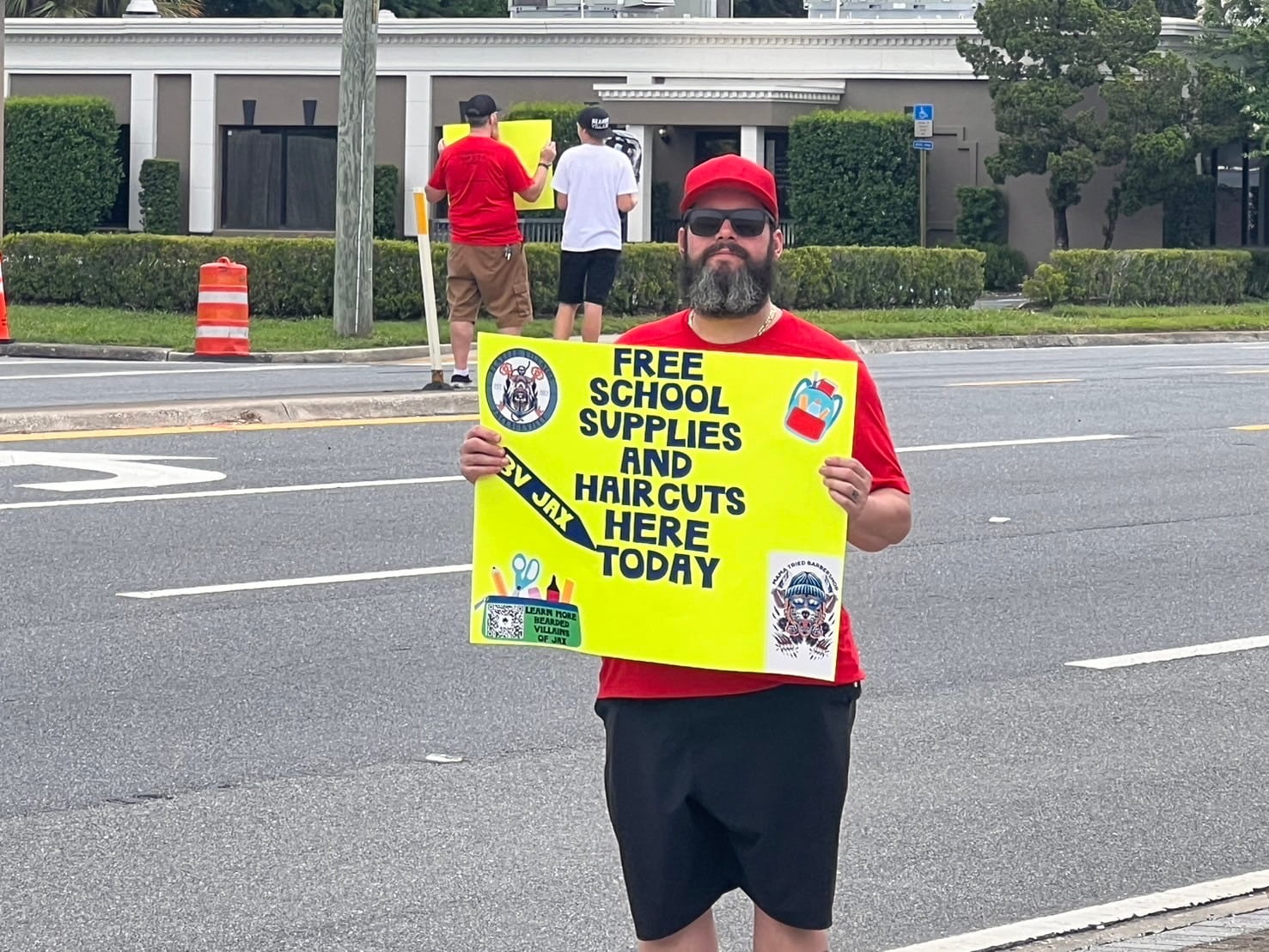 A bearded villain holding up a sign explaining the beards and backpacks charity event